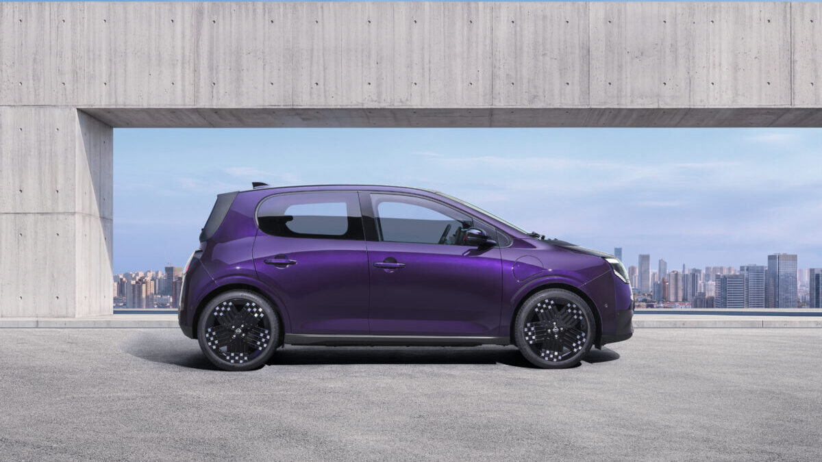 Nissan Pixo: el pequeño eléctrico que llega con 259 km de autonomia y una sorpresa enorme 2 Photograph showcasing a purple Nissan PIXO parked on a rooftop terrace. Side profile highlights aerodynamic shape, black alloy wheels concrete architectural frame, and city skyline backdrop.